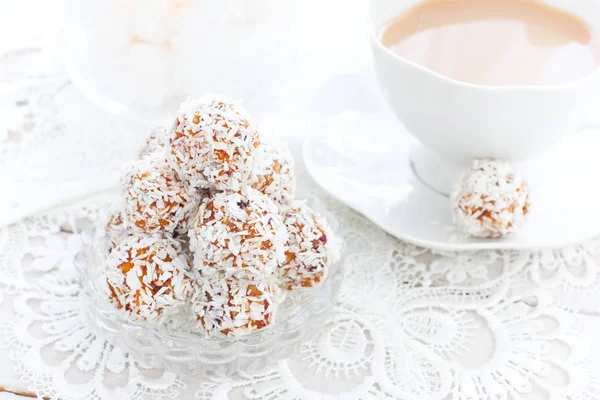 Полезные конфеты из сухофруктов в кокосовой стружке в виде шариков на белом столе, горизонтальный, копировальное пространство — стоковое фото