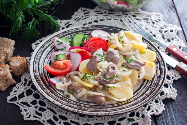 Cooked potatoes and chicken hearts on a plate with vegetable salad, horizontal