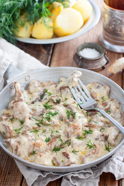 Forest mushrooms in sour cream sauce on a frying pan on a wooden table, selective focus — Stock Photo, Image