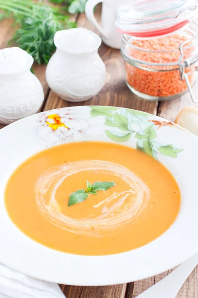 Красный чечевичный крем суп в белой тарелке на деревянном столе, избирательный фокус — стоковое фото