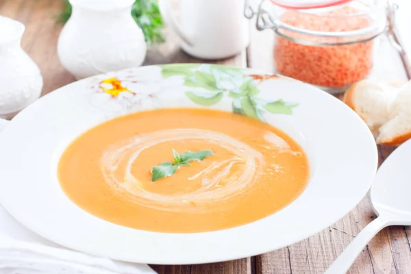 Красный чечевичный крем суп в белой тарелке на деревянном столе, горизонтальный — стоковое фото