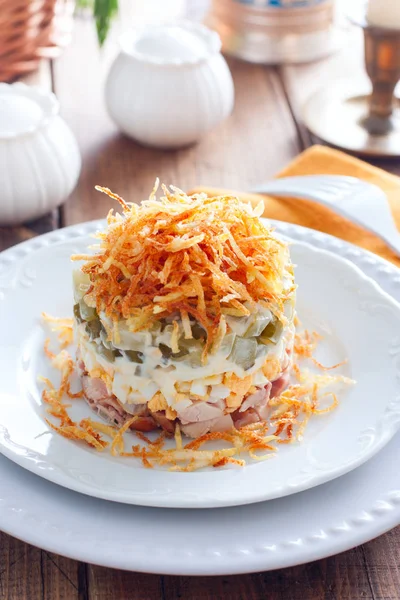 Салат с грибами, огурцами и курицей, украшенный жареным картофельным пирогом на белой тарелке, избирательный фокус — стоковое фото