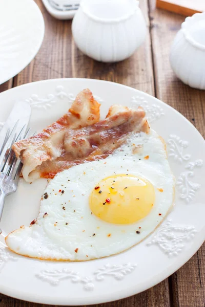 Desayuno de huevos fritos con tocino en una mesa de madera, enfoque selectivo — Foto de Stock