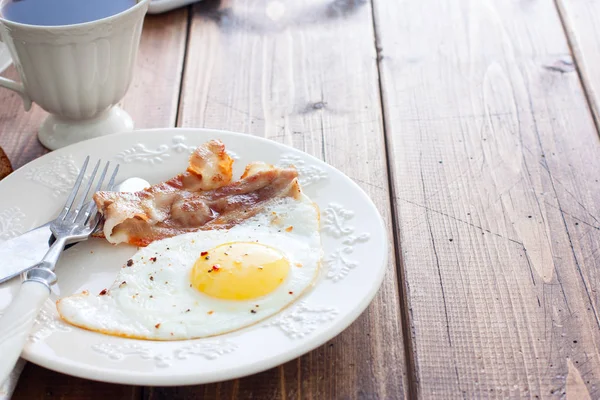 Traditionelles englisches Frühstück aus Spiegeleiern mit Speck auf einem Holztisch, waagerecht, Platz für Text — Stockfoto