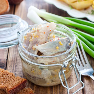 Ringa balığı, tahta bir masa, kare üzerinde cam bir kavanozhardal dilimleri marine