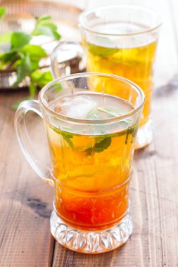 Ahşap bir masa üzerinde cam bardak limon ve nane ile Siyah buzlu çay, seçici odak