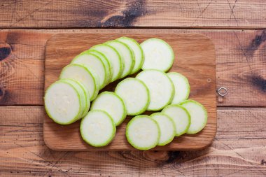 Ahşap bir tahta üzerinde daireler halinde dilimlenmiş çiğ kabak, üst görünümü