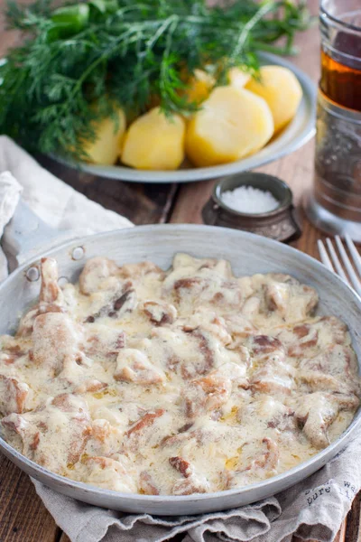 Forest mushrooms in sour cream sauce on a frying pan on a wooden table, selective focus — Stock Photo, Image