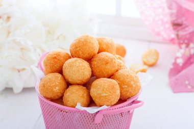 Beyaz bir masa üzerinde pembe bir sepet içinde ev yapımı peynir topları, yatay