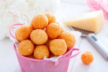 Beyaz bir masa üzerinde pembe bir sepet içinde ev yapımı peynir topları, yatay