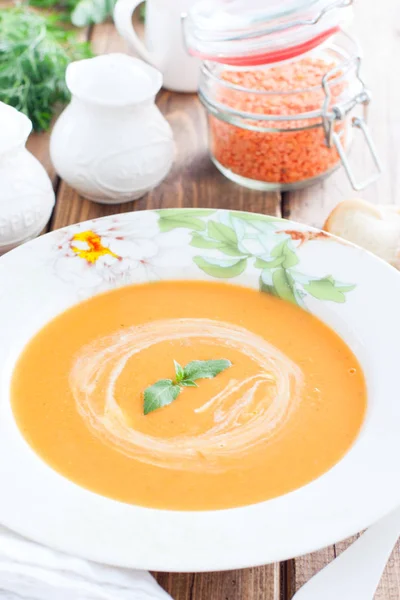 Красный чечевичный крем суп в белой тарелке на деревянном столе, избирательный фокус — стоковое фото