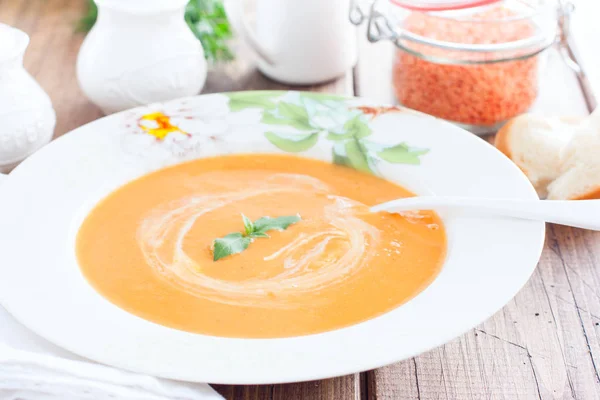 Red lentil cream soup in a white plate on a wooden table, horizontal — Stock Photo, Image