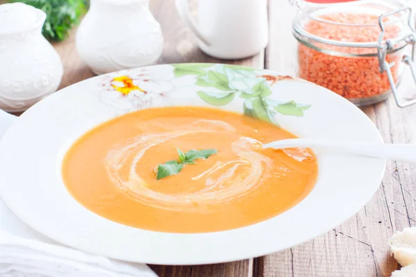 Красный чечевичный крем суп в белой тарелке на деревянном столе, горизонтальный — стоковое фото