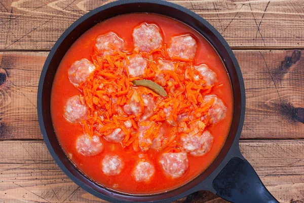 Step by step cooking meatballs with rice in tomato and vegetable sauce - step 5 - pouring raw meatballs with tomato and vegetables sauce, top view, horizontal