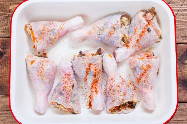 Step-by-step cooking chicken drumsticks stuffed with champignons - step 4 - stuffing chicken drumsticks and roasting in the oven, top view, horizontal
