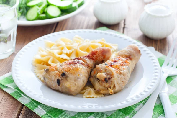 Tavuk bacakları makarna ile beyaz bir tabak üzerinde champignons ile doldurulmuş, yatay