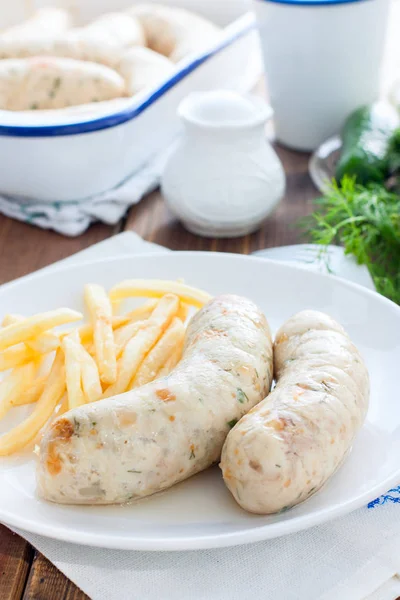Homemade kupaty with chicken and french fries on a white plate, selective focus — Stock Photo, Image