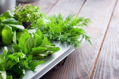 Ahşap bir masa üzerinde metalik formda taze otlar, yatay, kopyalama alanı