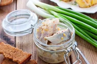 Ringa balığı, tahta bir masa üzerinde cam bir kavanozhardal dilimleri marine, yatay