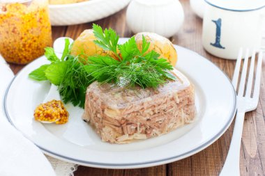 Ahşap arka plan üzerinde plaka üzerinde yeşillik ve yumurta ile dekore edilmiş ev yapımı jöle tavuk yakın. Soğuk Et Yemekleri. Üstte görüntü