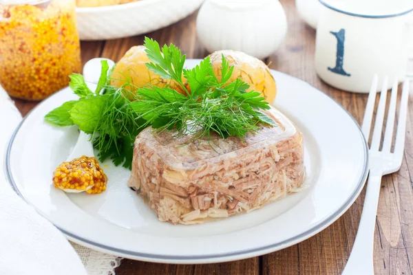 Ahşap arka plan üzerinde plaka üzerinde yeşillik ve yumurta ile dekore edilmiş ev yapımı jöle tavuk yakın. Soğuk Et Yemekleri. Üstte görüntü