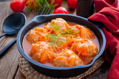 Ahşap bir masa üzerinde dökme demir tava domates sosu pirinç ile Köfte, yatay