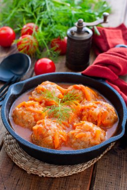 Domates soslu pilavlı köfte ve siyah dökme demir tavada sebzeler, seçici odak