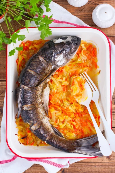 Baked grass carp with enameled vegetables on a wooden table, top view, selective focus