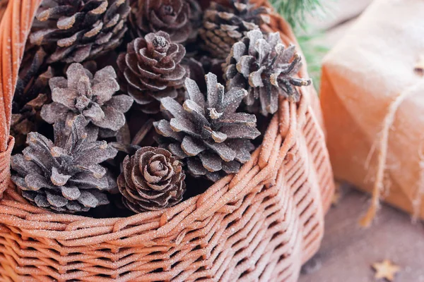 Christmas basket with pine cones on a wooden table, close-up, horizontal, copy space