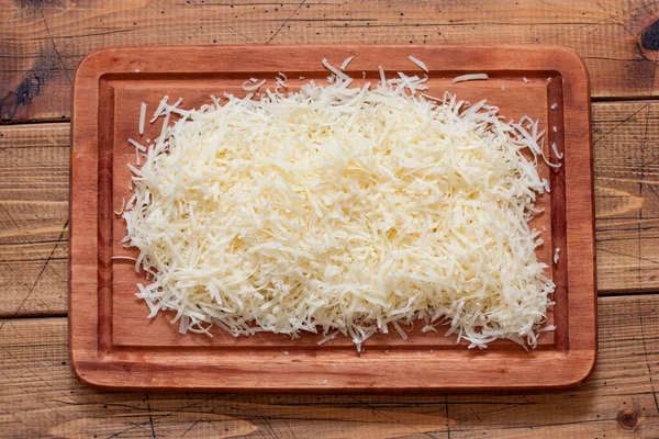Cooking oven-baked cheese balls step by step, step 2 - grated parmesan on a wooden board, horizontal