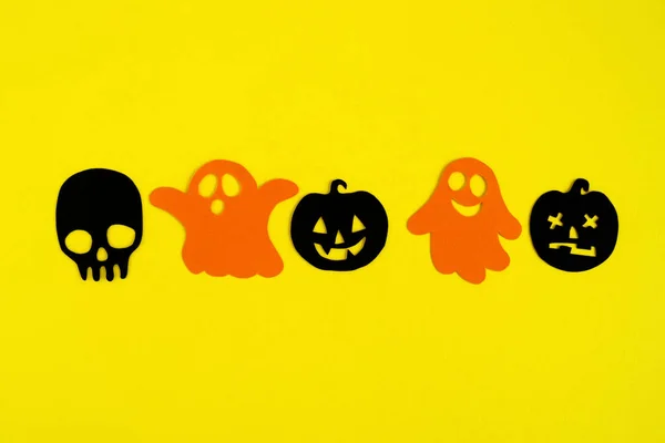 ハロウィーンの休日の装飾 オレンジ色の紙幽霊と黒い紙のカボチャと背景が黄色 上面に頭蓋骨 — ストック写真