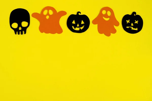 ハロウィーンの休日の装飾 オレンジ色の紙幽霊と黒い紙のカボチャと背景が黄色 上面に頭蓋骨 — ストック写真