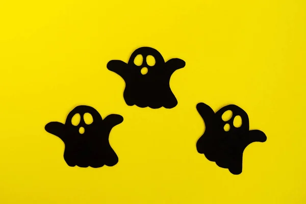 ハロウィーンの休日の装飾 黄色の背景は 上面に つの黒い紙幽霊 — ストック写真
