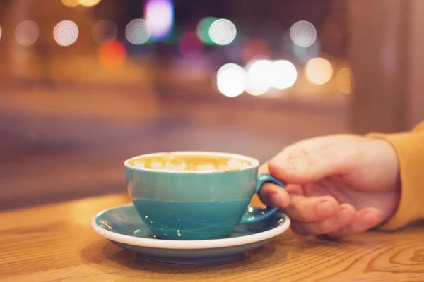 Χέρι Ανθρώπου Φλιτζάνι Καφέ Ένα Καφέ Φόντο Φώτα Της Πόλης — Φωτογραφία Αρχείου