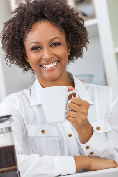 美しい幸せな混血のアフリカ系アメリカ人女の子やコーヒーのマグカップを飲む彼女のキッチンで完璧な歯を持つ若い女性 — ストック写真