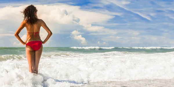 青空のパノラマのバナー画像と捨てられた熱帯ビーチでサーフィン波でビキニで美しい若い女性のパノラマ リアビュー — ストック写真