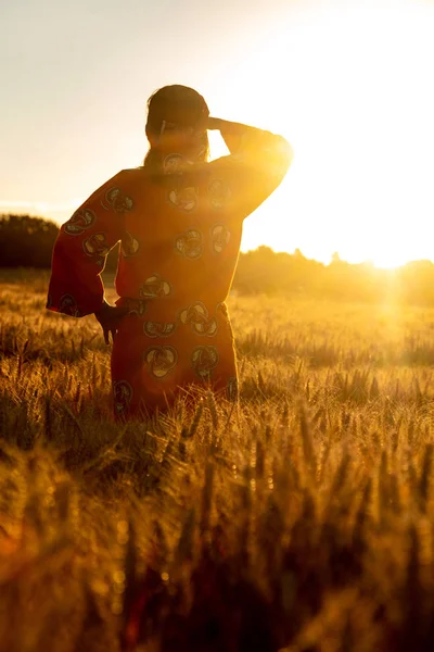 Afrikanerin in traditioneller Kleidung steht bei Sonnenuntergang oder Sonnenaufgang auf einem Feld — Stockfoto