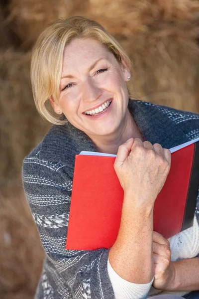 Щаслива жінка середнього віку читає книгу або щоденник — стокове фото