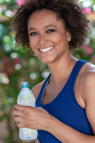 African American biracial kobieta wykonywania wody pitnej butelka — Zdjęcie stockowe