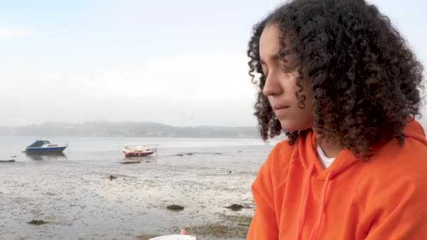 美丽的混合种族非洲裔美国女孩少女少女穿着橙色头套 喝外卖咖啡的港口看起来悲伤或周到 — 图库视频影像