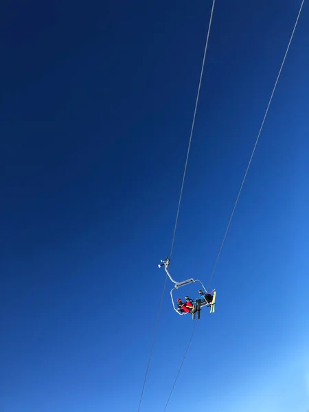 滑雪者在滑雪椅升降机在与蓝天的度假胜地 — 图库照片
