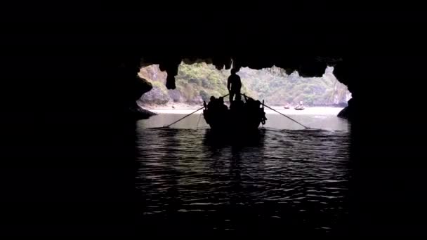ハロン湾 の国立公園 ベトナムの石灰岩の島の洞窟を介して導かれている伝統的なローカル ボートで観光客 — ストック動画