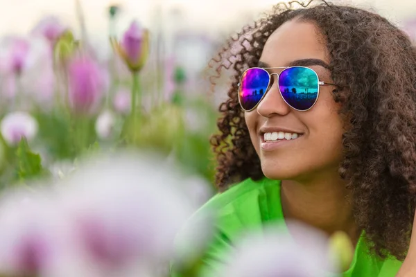 Biracial joven chica adolescente en campo de flores usando s — Foto de Stock