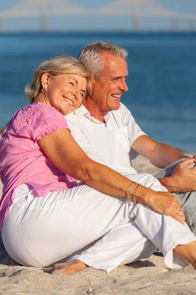 Feliz casal sênior sentado rindo sorrindo em uma praia — Fotografia de Stock