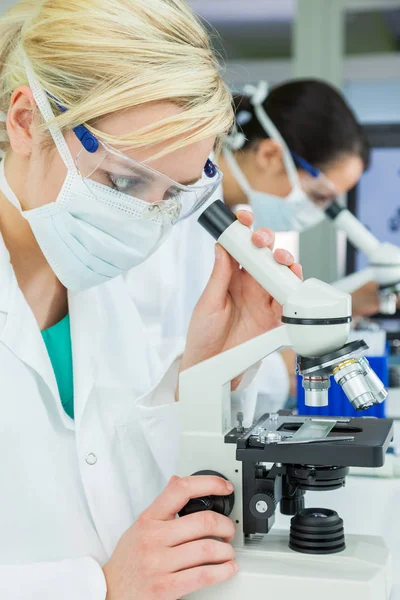 Vrouwelijk wetenschappelijk onderzoeksteam wetenschappers die microscopen — Stockfoto