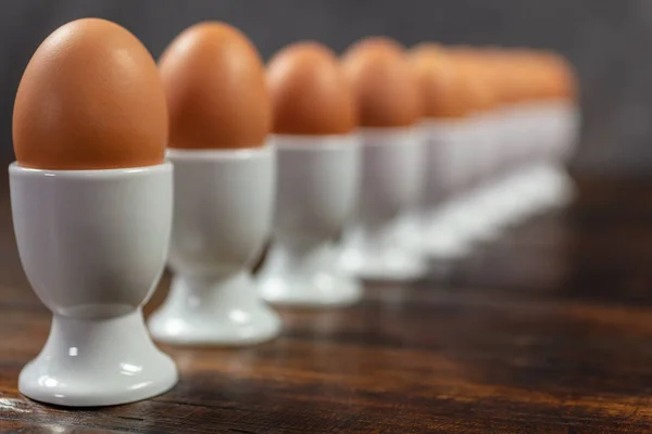 Tien gekookte eieren in eier kopjes in een lijn op een tafel — Stockfoto