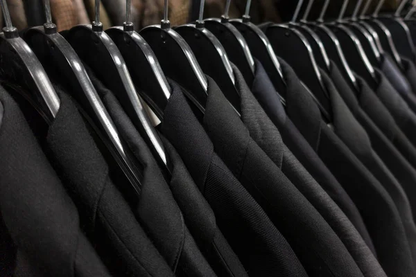 Trajes masculinos oscuros para hombre en perchas en un armario de tienda Closet Rail — Foto de Stock