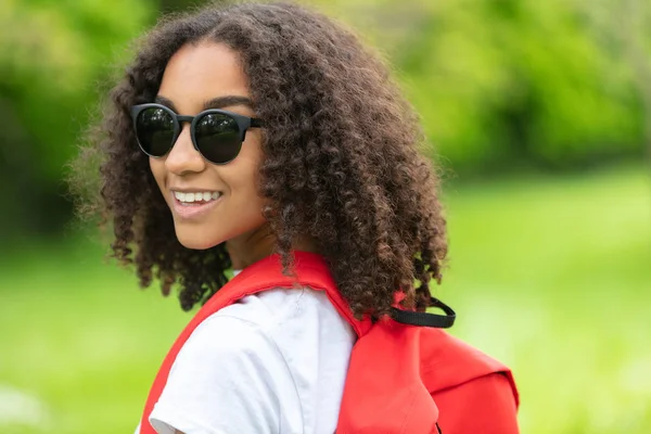 Blandad ras afroamerikansk flicka tonåring vandring med röd ryggsäck och solglasögon — Stockfoto