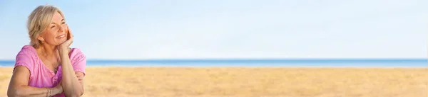 Панорама Приваблива старша жінка сидить на пляжі Панорамний веб-банер — стокове фото