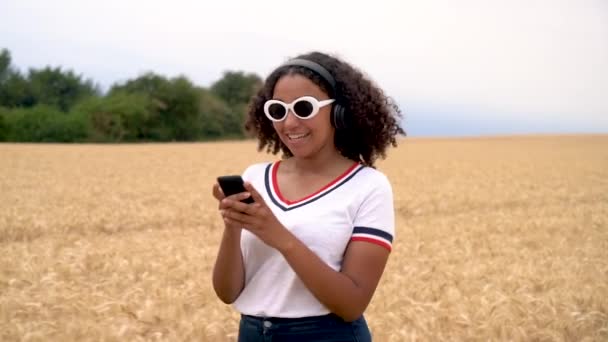 혼합된 아프리카계 미국인 여자의 필드에 셔츠와 선글라스 그녀의 헤드폰에서 음악을 — 비디오